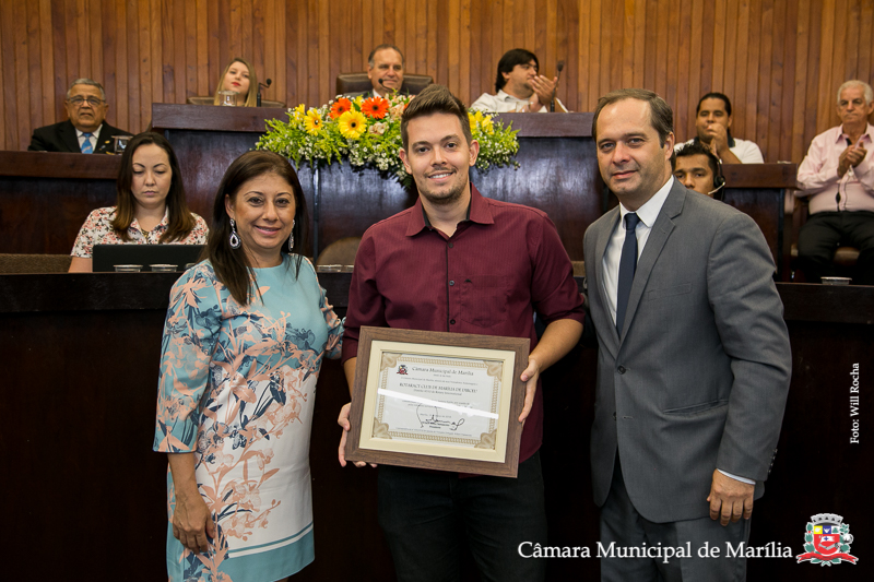 Vereadores professora Daniela e Danilo da Saúde entregam homenagem ao representante do Rotaract Marília de Dirceu, Lucas Alexandre Gonzales Oliveira.